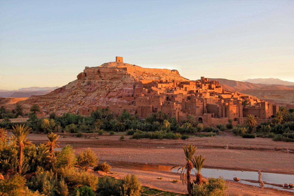 Panoramic view of Ait Ben Haddou kasbah with Atlas Mountains in background at sunset